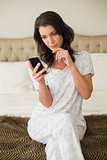 Thinking pretty brown haired woman using a mobile phone
