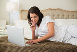 Thinking pretty brown haired woman using a laptop