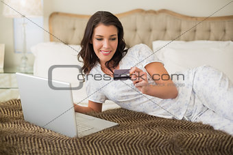 Cheerful pretty brown haired woman shopping online with her laptop