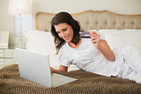 Joyful pretty brown haired woman shopping online with her laptop