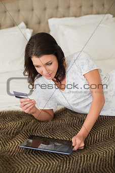 Calm pretty brown haired woman shopping online with her tablet pc