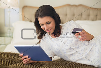 Joyful pretty brown haired woman shopping online with her tablet pc