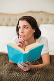 Thoughtful pretty brown haired woman holding a book