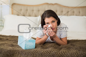 Depressed pretty brown haired woman wiping her eyes with a tissue