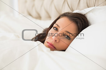 Relaxed pretty brown haired woman lying in her bed