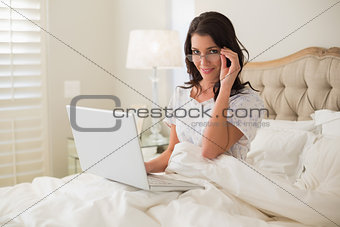 Cheerful pretty brown haired woman using a laptop