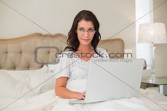 Relaxed pretty brown haired woman typing on a laptop