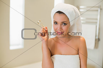 Happy natural brown haired woman using eyelash curler
