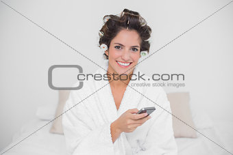 Smiling natural brunette holding smartphone