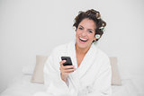Laughing natural brunette holding smartphone
