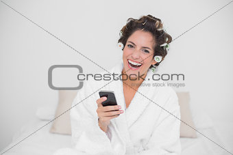 Laughing natural brunette holding smartphone