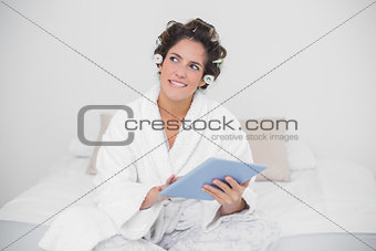 Pensive natural brunette holding tablet