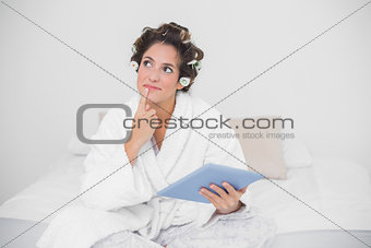 Thoughtful natural brunette holding tablet