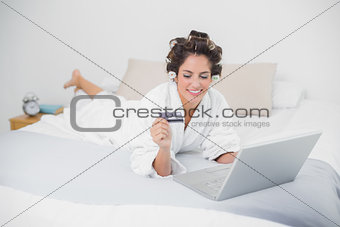 Happy natural brunette using credit card and laptop