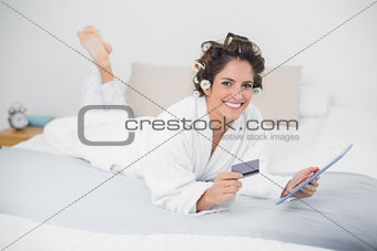 Smiling natural brunette using tablet and credit card