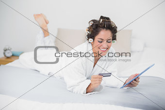 Happy natural brunette using tablet and credit card