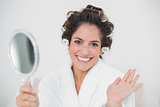Cheerful natural brunette holding mirror and waving