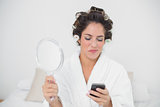 Smiling natural brunette holding mirror and smartphone