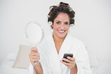 Content natural brunette holding mirror and smartphone