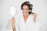 Cheerful natural brunette using brush and mirror