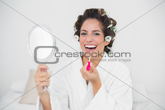 Laughing natural brunette applying lip gloss