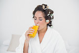Calm natural brunette drinking glass of orange juice