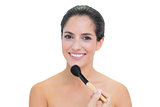 Cheerful bare brunette holding powder brush