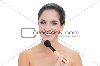 Cheerful bare brunette holding powder brush