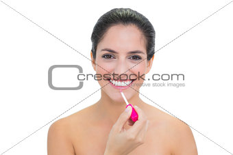 Smiling bare brunette applying lip gloss