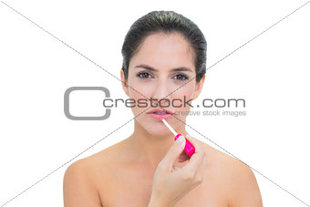 Stern bare brunette applying lip gloss