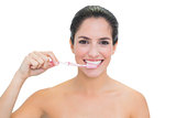 Smiling bare brunette using toothbrush