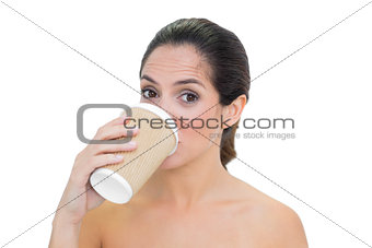 Content bare brunette drinking from disposable cup