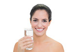 Smiling bare brunette holding glass of water