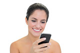 Smiling bare brunette using smartphone