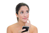 Pensive bare brunette using smartphone