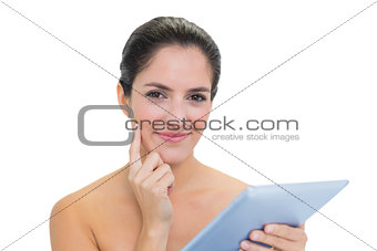 Pensive bare brunette using tablet