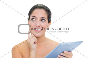 Thoughtful bare brunette using tablet