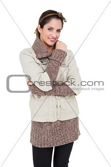 Smiling cute brunette in winter fashion touching her right shoulder