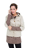 Upset cute brunette in winter fashion phoning