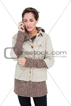Upset cute brunette in winter fashion phoning