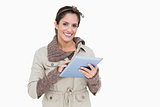 Smiling cute brunette in winter fashion holding tablet