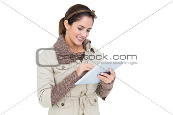 Smiling cute brunette in winter fashion using tablet