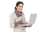 Happy cute brunette in winter fashion holding laptop