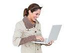 Happy cute brunette in winter fashion using laptop