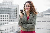 Cheerful gorgeous brunette in winter fashion holding smartphone