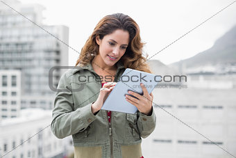 Content gorgeous brunette in winter fashion using tablet