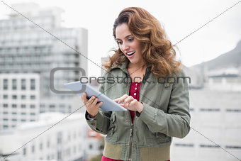 Happy gorgeous brunette in winter fashion using tablet