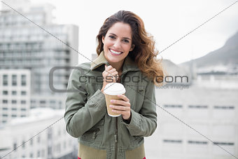 Cheerful gorgeous brunette in winter fashion holding disposable cup