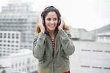 Smiling gorgeous brunette in winter fashion listening to music