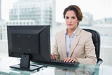 Stern businesswoman sitting looking at camera